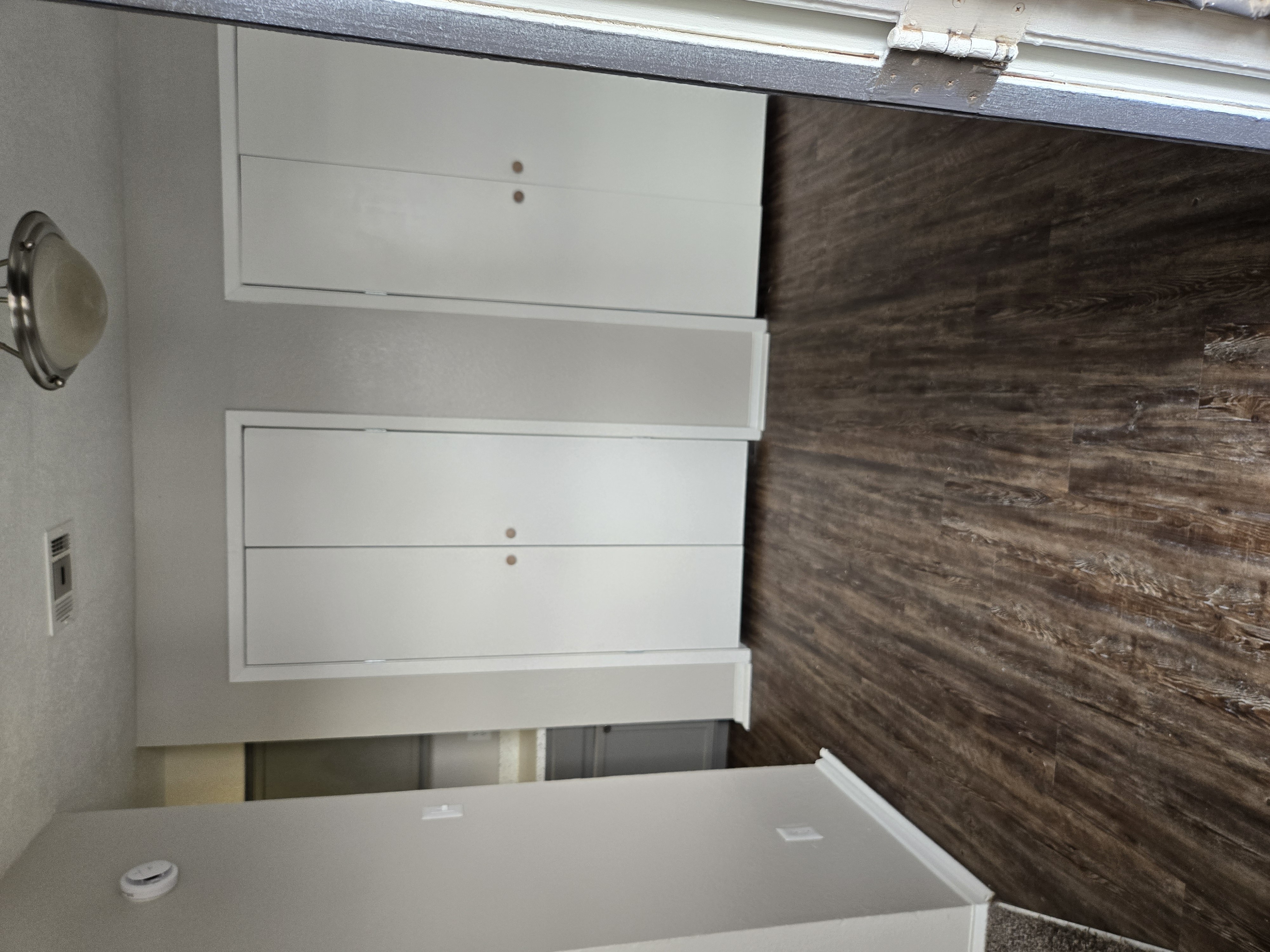 A white cabinet with two drawers is mounted on a wall.